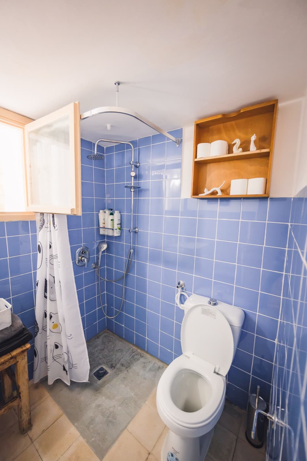 Blue-tiled bathroom with walk-in shower, one of two bathrooms in the apartment