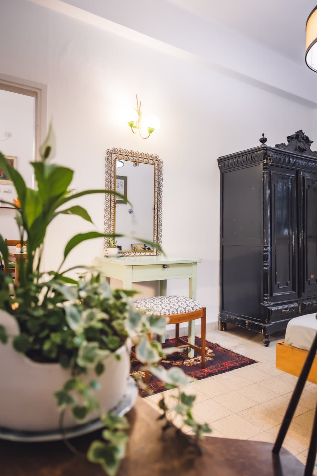 Bedroom corner with antique wardrobe, vanity table and plants in the Haifa apartment